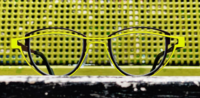 An image of black and lime green Theo eyeglasses against a textured background. An image of black and lime green Theo eyeglasses against a textured background.