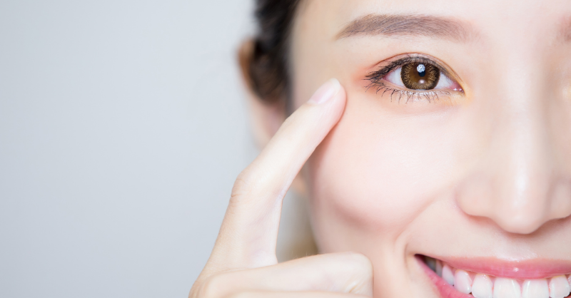 A woman smiling, pointing towards her eye