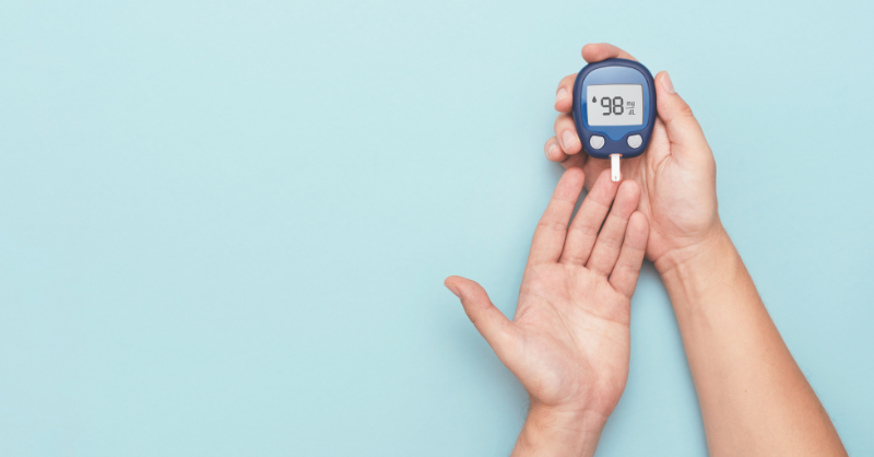 A diabetes blood sugar monitor device resting on a pair of hands