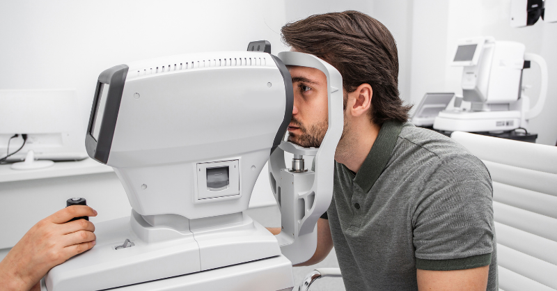A man looking into a machine during a comprehensive eye exam