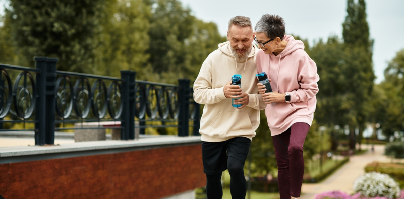 Couple shares laughs while jogging, enjoying their active lifestyle in a peaceful setting.