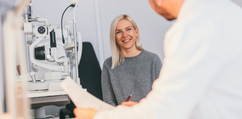 A young woman sat talking to her eye doctor during an eye examination.
